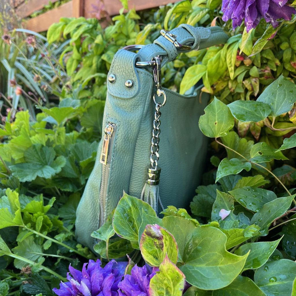 Sage green Elsa bag amongst foliage