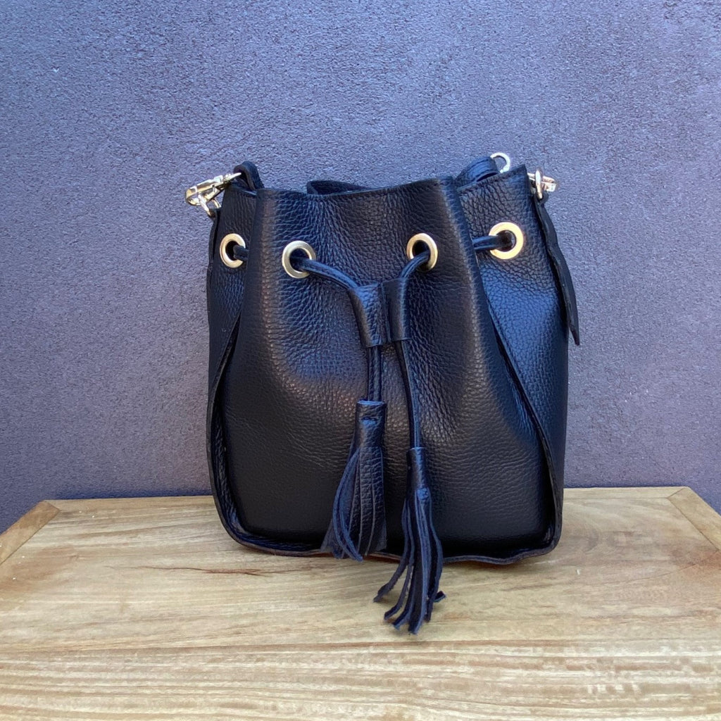 Black leather bucket bag with drawstring on a wooden surface 
