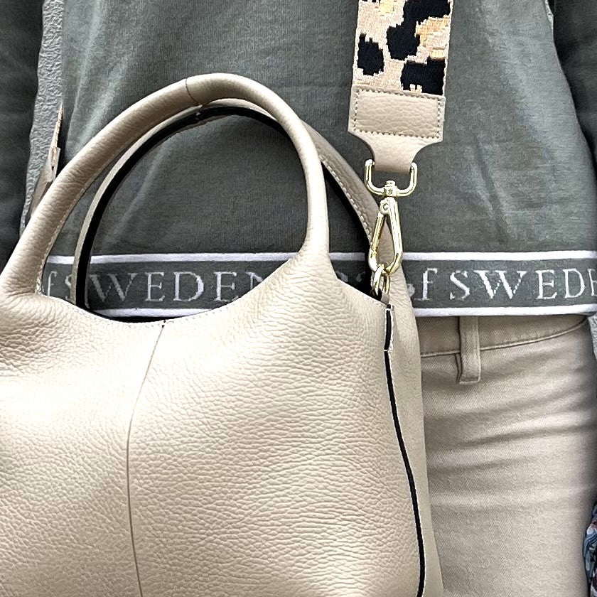 Woman wearing the Leah tote in beige with a fabric strap (additional cost)