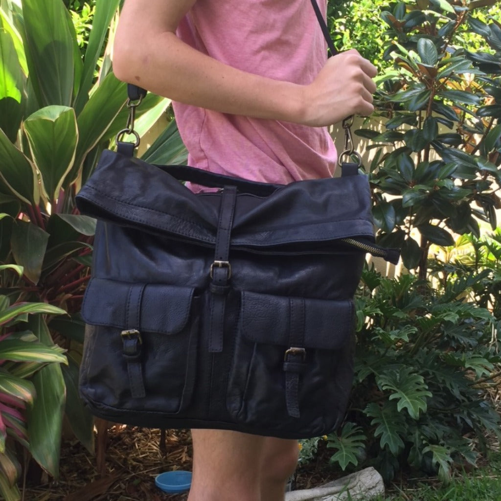 Man holding the Liam backpack over his shoulder using the longer strap