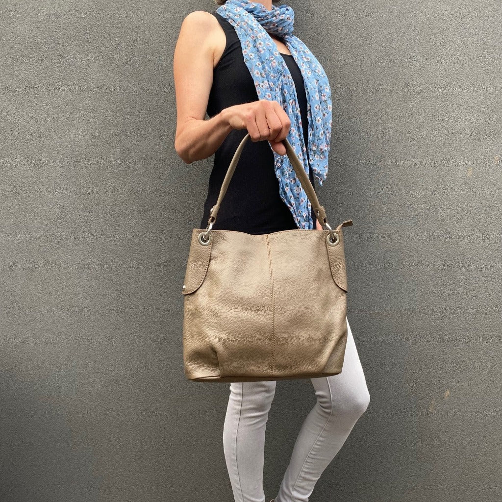 Woman holding the Kelli bag in dark taupe or burlywood