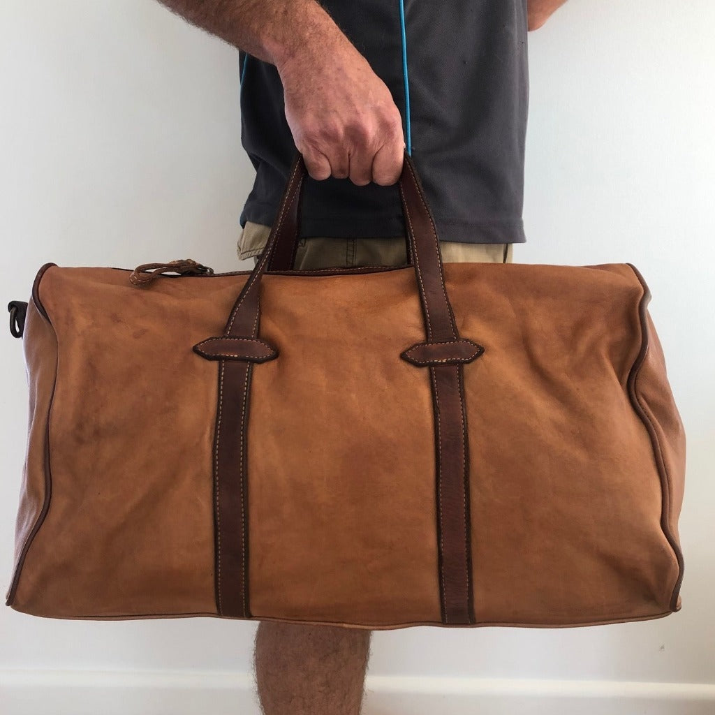 Man holding the Raymond bag in sienna