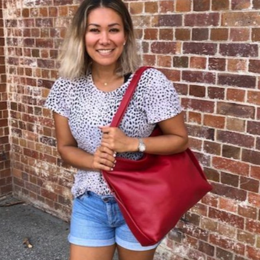 Woman holding the red Adelaide bag over her shoulder