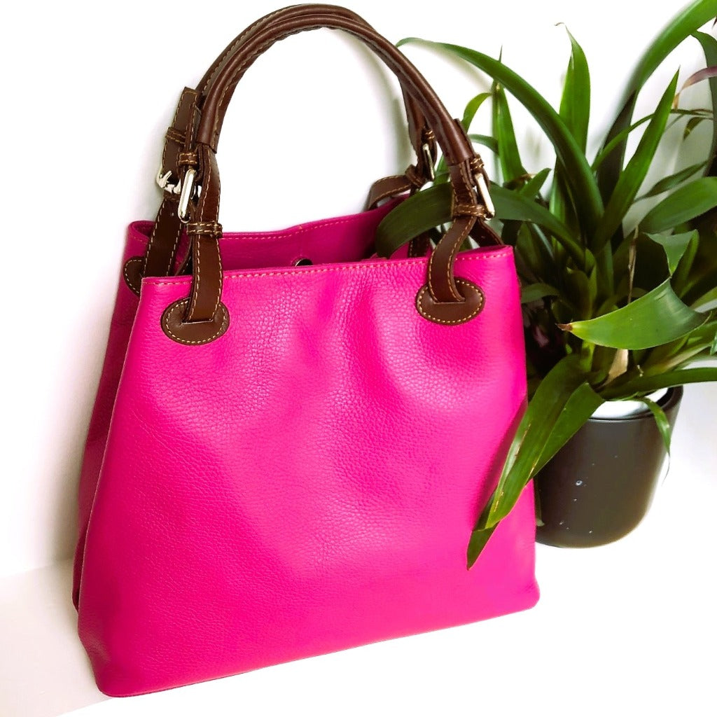 Dawn bag in Fuchsia next to a plant