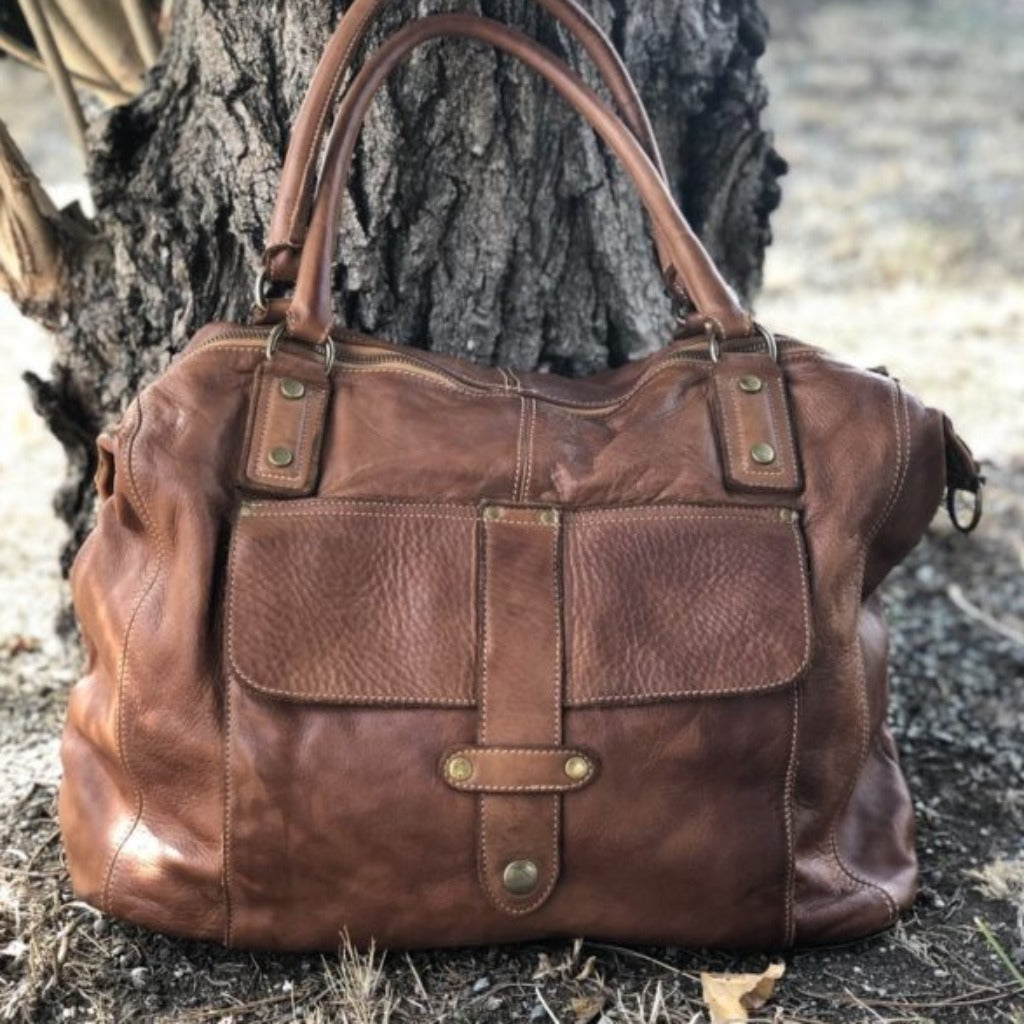 The Page bag in natural sitting against a tree
