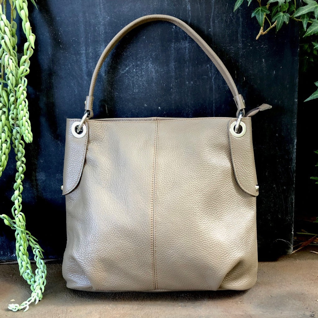 The Kelli bag in burlywood outside against a wall