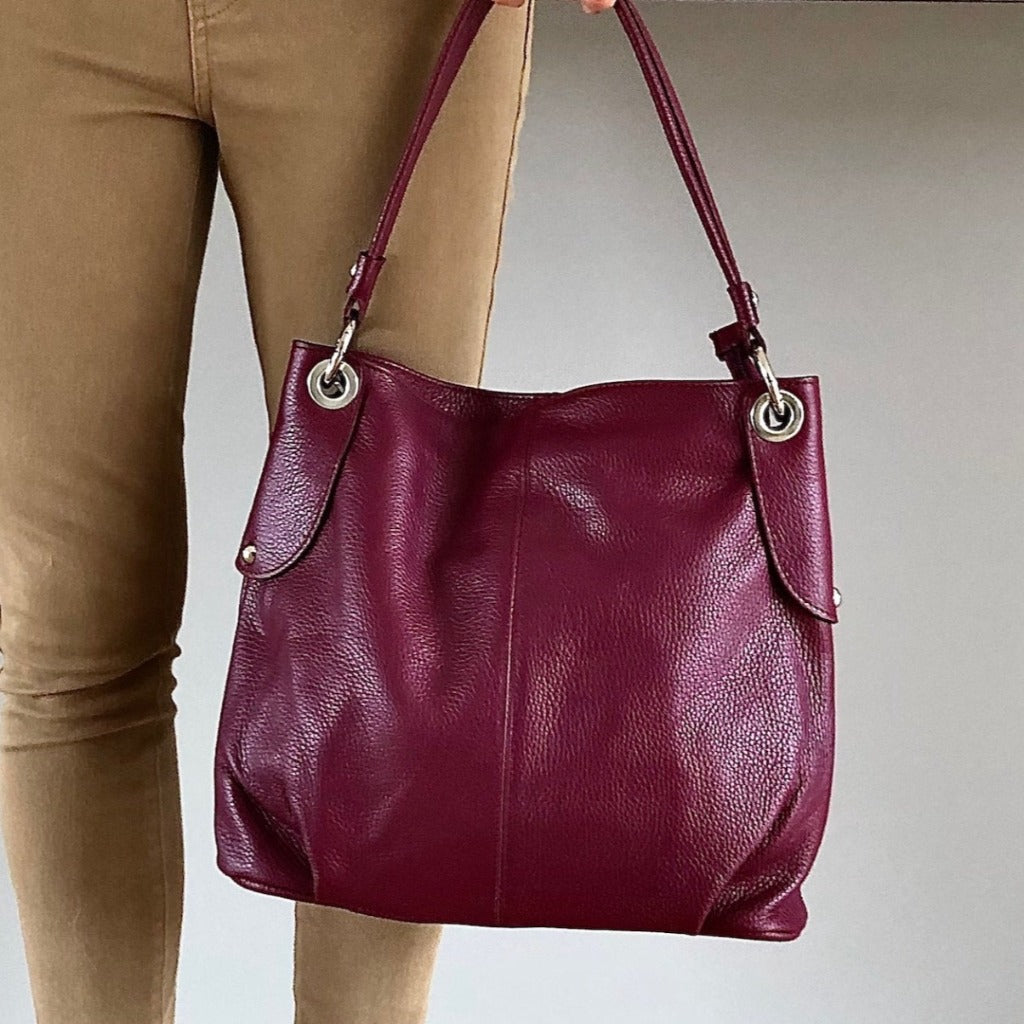 Woman holding the Kelli bag in Burgundy